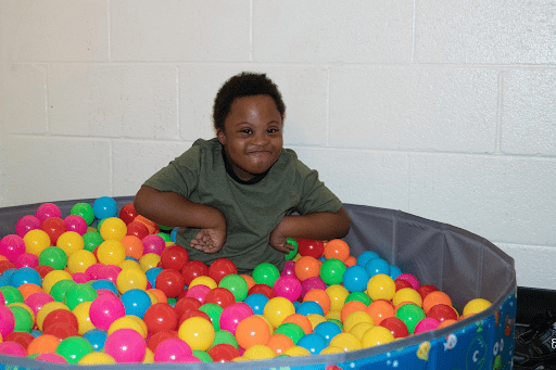 Child playing in pit filled with plastic balls