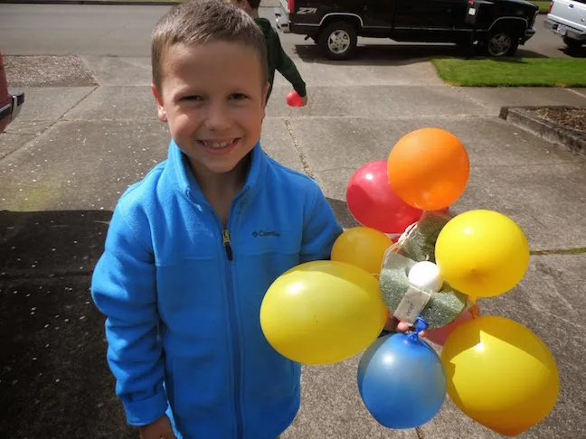 child holding an egg drop challenge, a foam surrounded by balloons