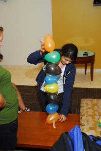 A girl is seen stacking balloons on top of one another. 