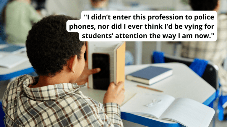 Student looking at phone behind book in classroom