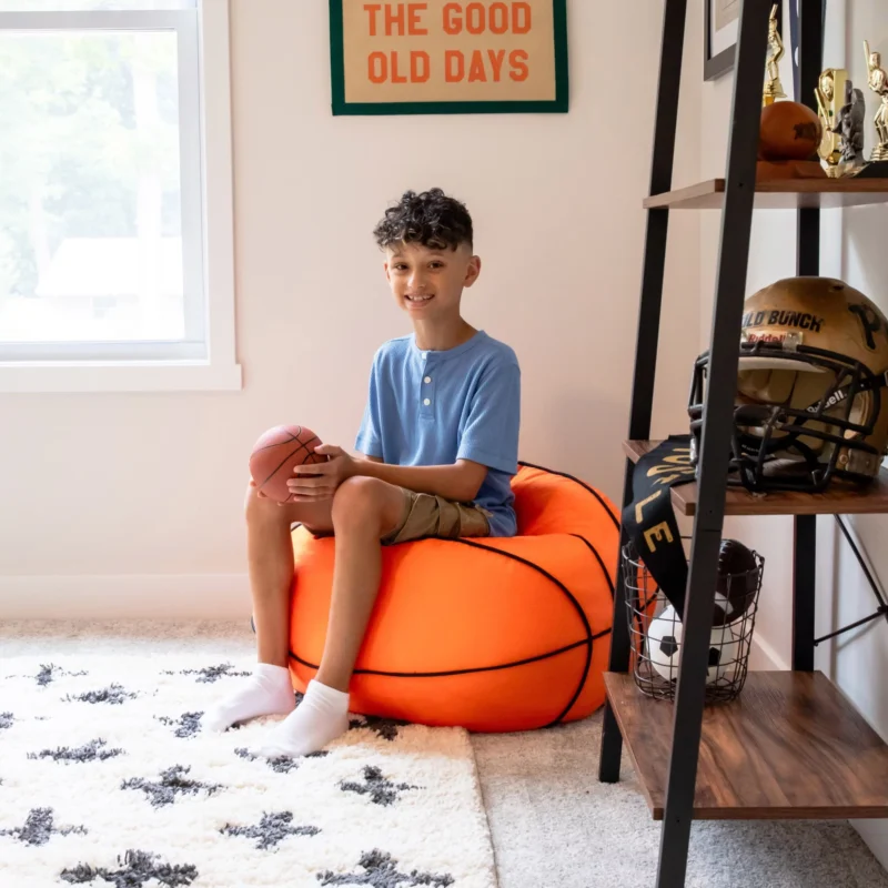 A boy sits on a beanbag chair that looks like a basketball.