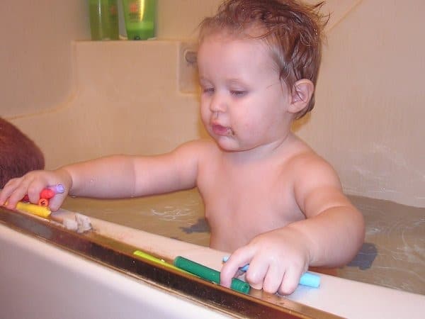 child drawing in the bath with crayons 