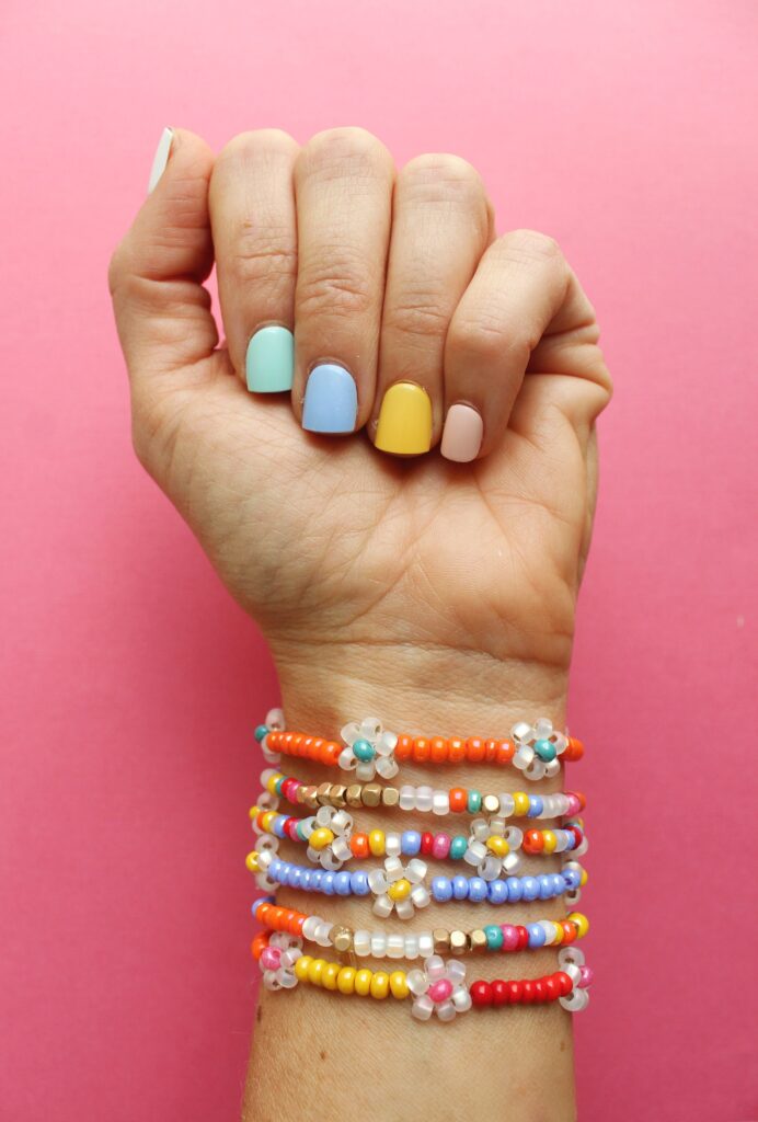 A hand with painted nails shows off a pretty stack of beaded bracelets