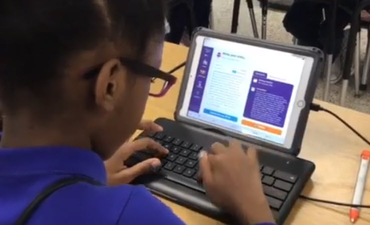 Student writing a journal entry using a tablet and keyboard