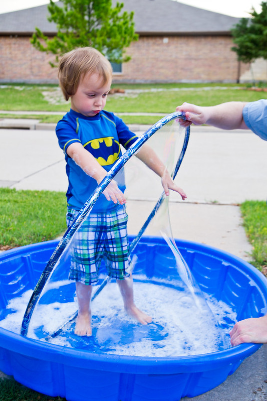 Boy making large bubble with hula hoop- summer activities for kids
