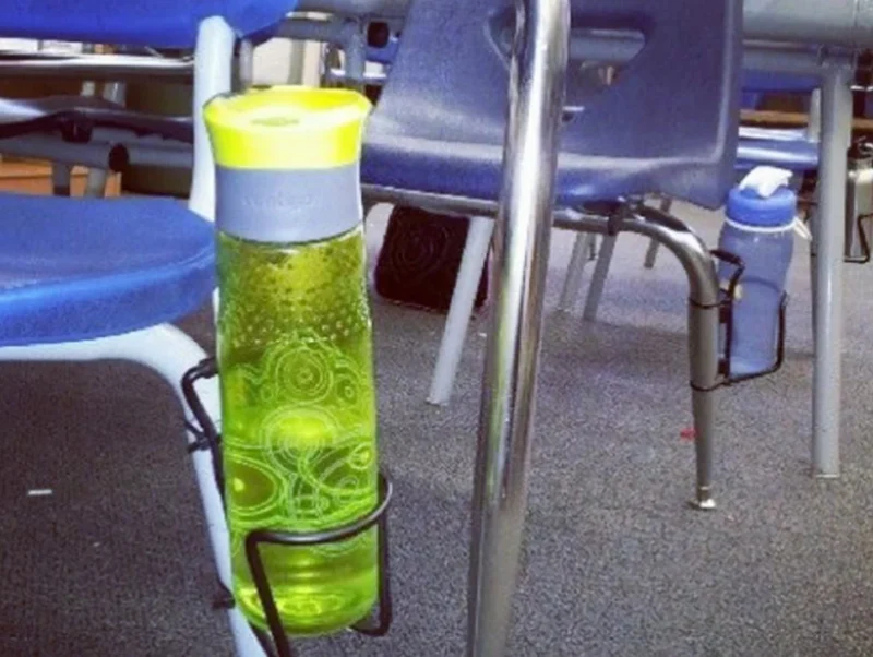 A water bottle is attached to a desk chair by a metal bike water bottle holder that has been secured to a desk leg.