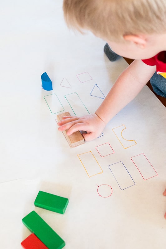 child matching blocks with pictures of blocks on butcher paper in a preschool activity