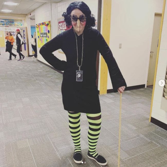 Woman wearing black dress, yellow and black striped stockings, and long fake nose (Book Character Costume Ideas)