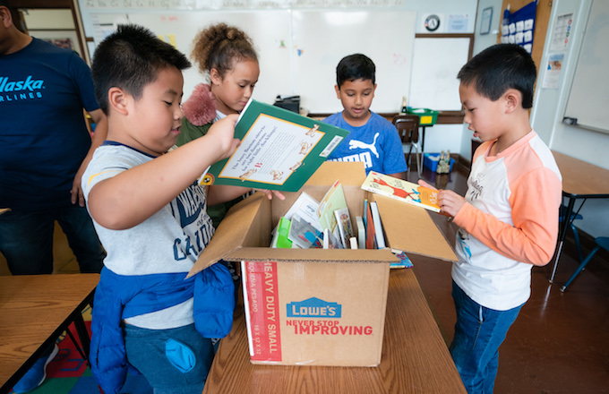 Students gathered around a box of books checking out what's inside