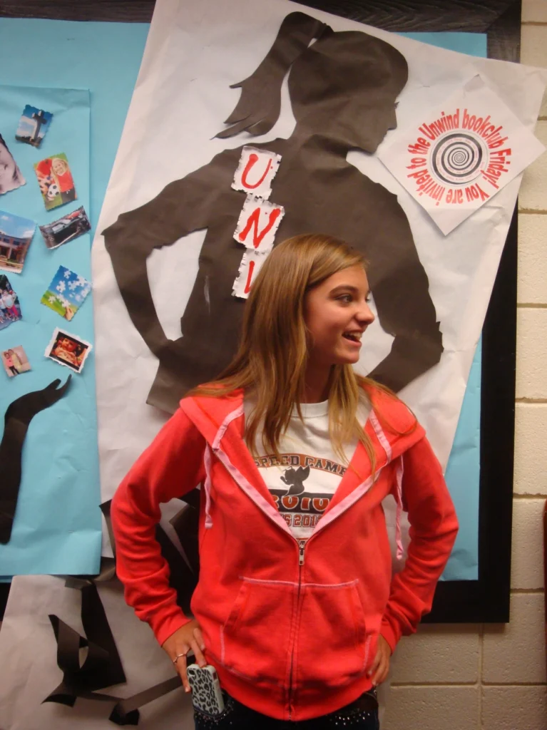 student standing in front of a poster of a book cover 