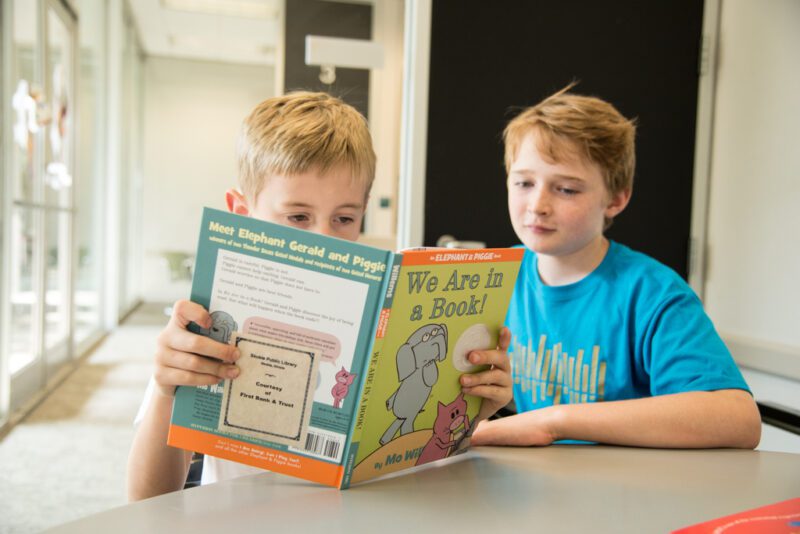 young boy reading with a buddy, as an example of social emotional learning activities