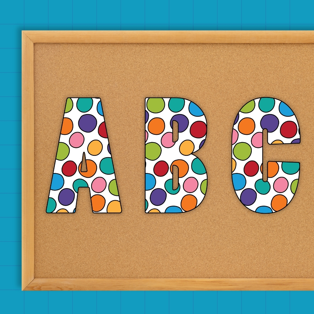 Bright polka dot letters A, B, and C pinned to a cork display board