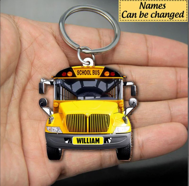 Hand holding a school bus key chain with personalized name of driver on license plate.