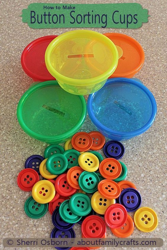 Several small containers in different colors have a slit on the top. Multi colored buttons are piled up by them.