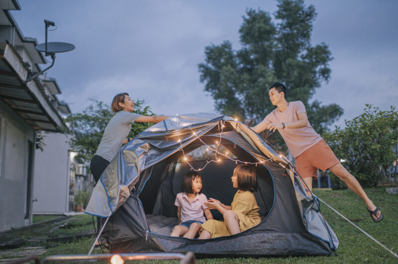 Asian chinese family putting on string light decorating camping at backyard of their house staycation weekend activities