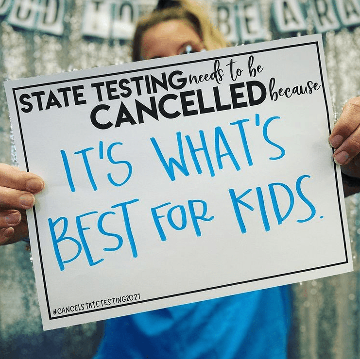 Teacher holding sign that supports canceling state tests
