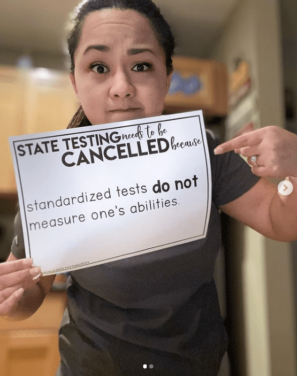 Teacher holding sign against standardized tests