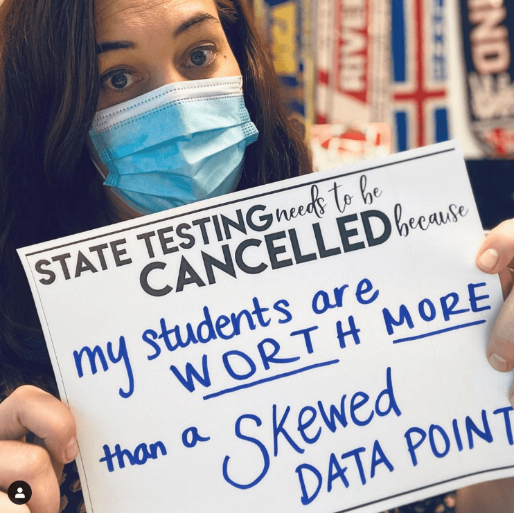 Teacher holding sign about canceling state tests