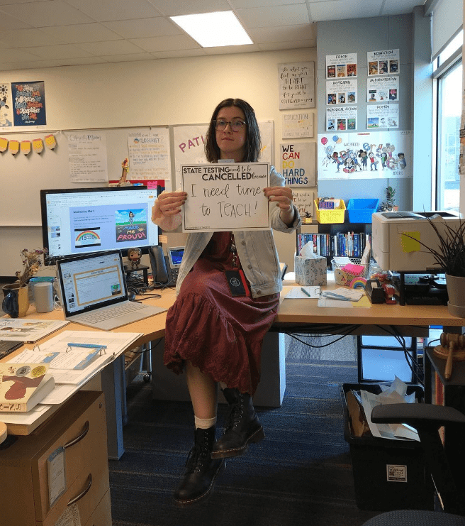 Teacher holding a sign to cancel state testing