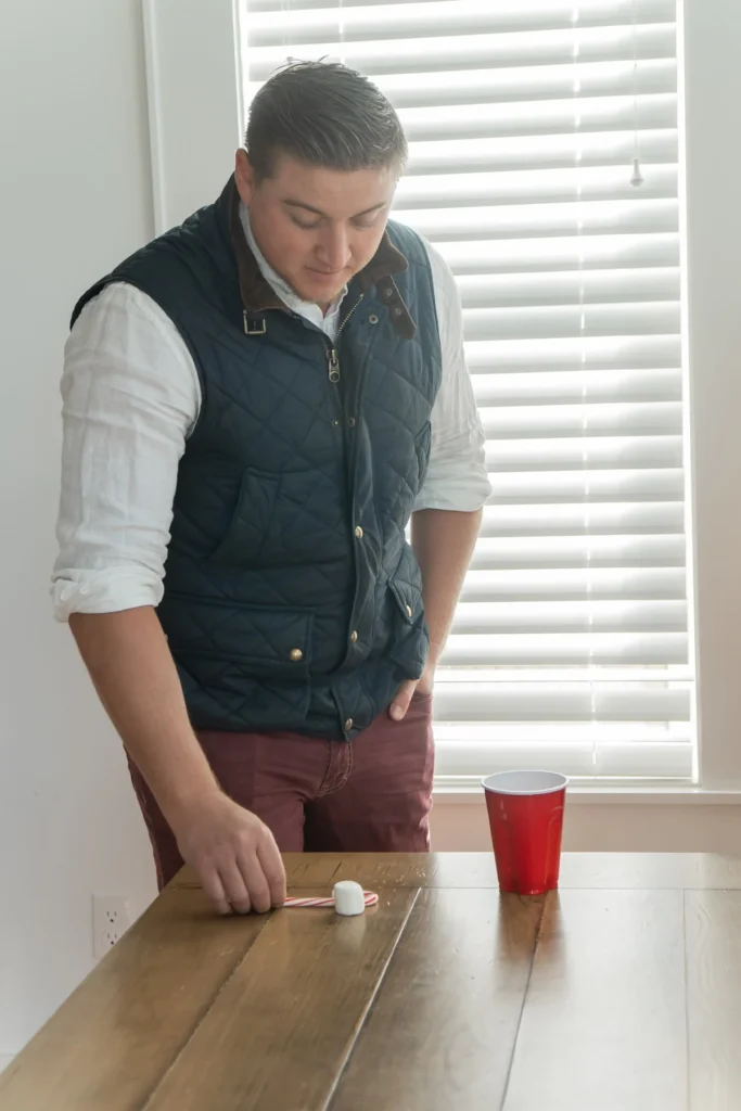 person playing candy cane and marshmallow shuffle board for a candy cane game