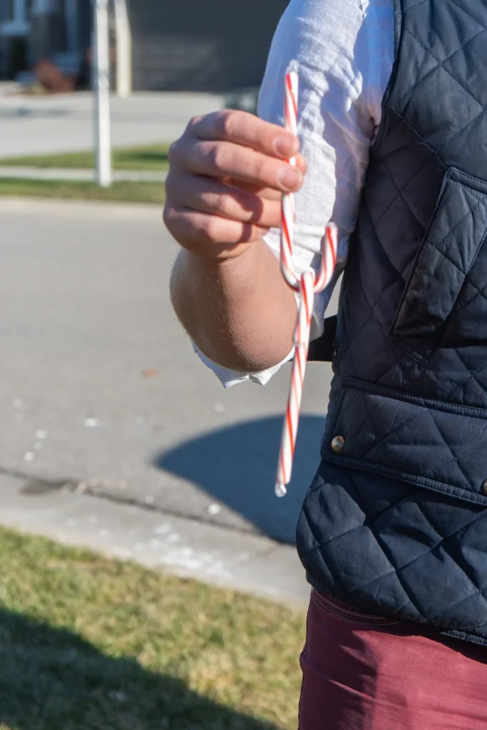 person holding two candy canes one balanced on the other for a candy cane game idea 
