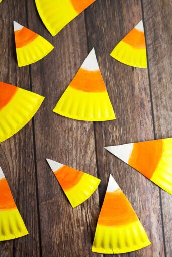 Fall art projects include candy corn like these made from paper plates cut to shape and painted white, orange, and yellow.