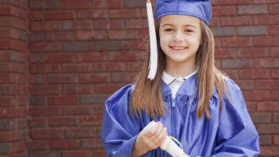 Kindergarten girl wearing blue cap and gown.