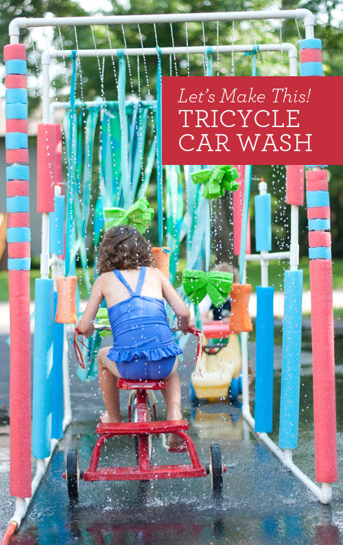 child driving a tricycle through a car wash made from p v c pipes and pool noodles for a water activity