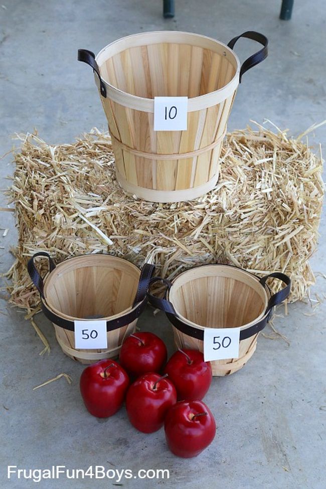 Three bushel fruit baskets labeled with point values, with a bale of hay and four red apples