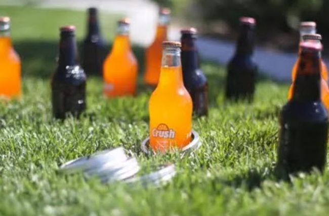 Bottles of soda in the grass with small plastic rings set up for a carnival game