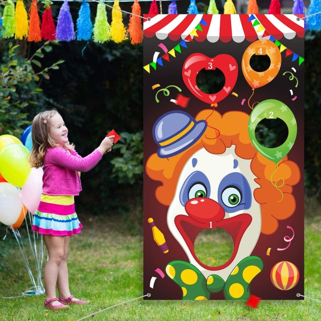 Child throwing a beanbag into the open mouth of a clown printed on a vinyl banner 
