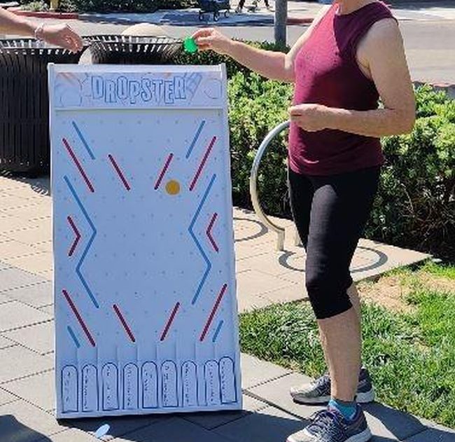 Woman dropping a disk into a board covered in pegs that guide it into a slot below