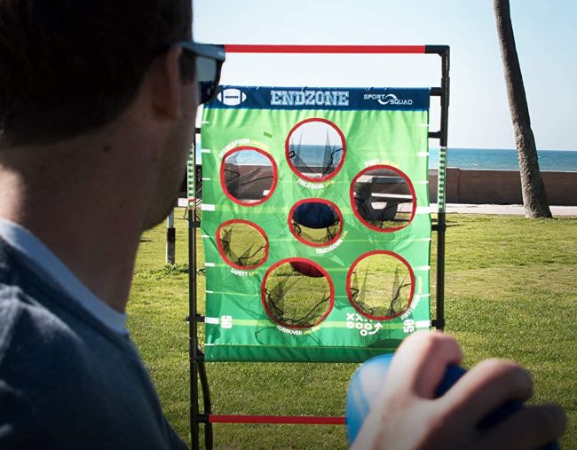 Man preparing to throw a football at a target with a variety of holes