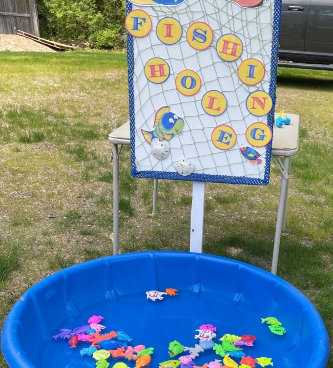 Kiddie pool filled with plastic fish, next to a sign that reads Fishing Hole