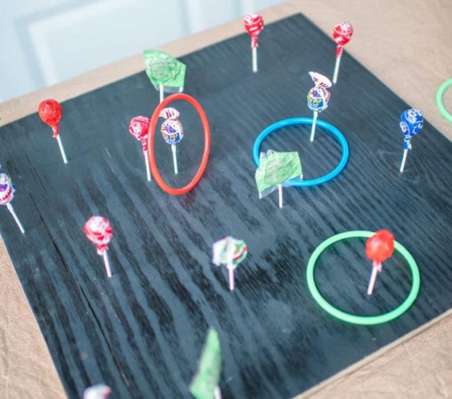 Carnival game made with lollipops stuck into a board to sit upright by their sticks, with colorful plastic rings