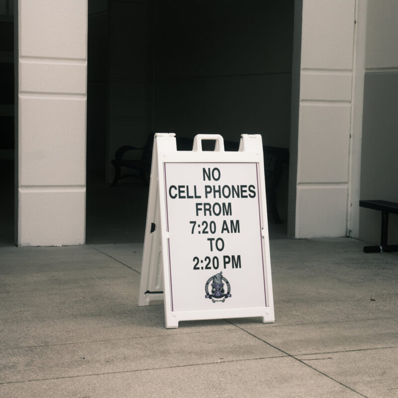 sign outside a school that reads no cell phones from 7:30 to 2:20 PM 