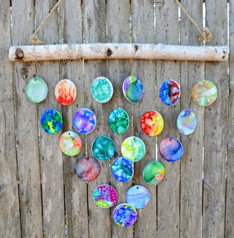 Hand-painted ceramic wind chimes hanging in a triangular shape on a wooden fence as an example of class auction projects.
