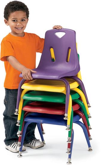 Young student in an orange shirt stacks colorful plastic chairs