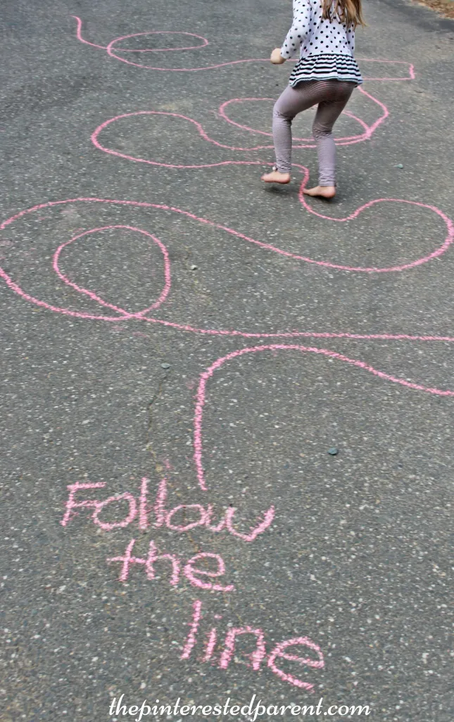 Child walking on squiggly chalk line, as an example of gross motor activities