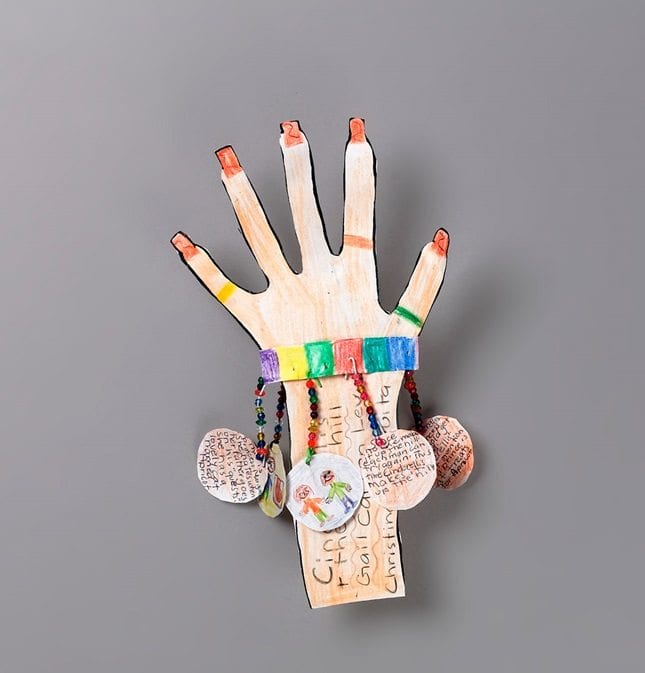 A decorated paper hand with paper charms hanging off of it