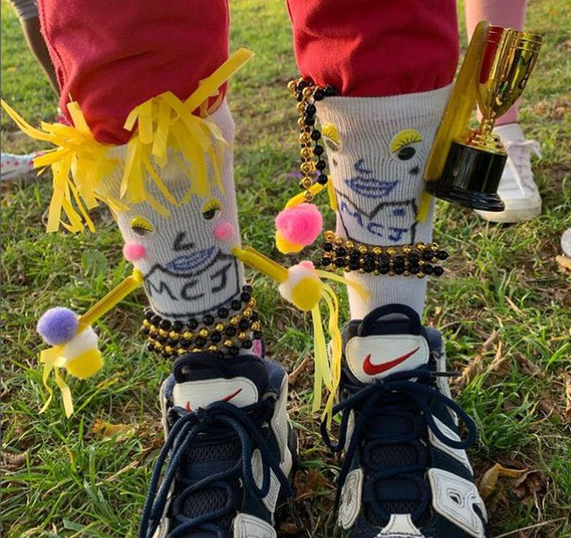 Socks decorated to look like little cheerleaders with hands holding pom poms and a trophy