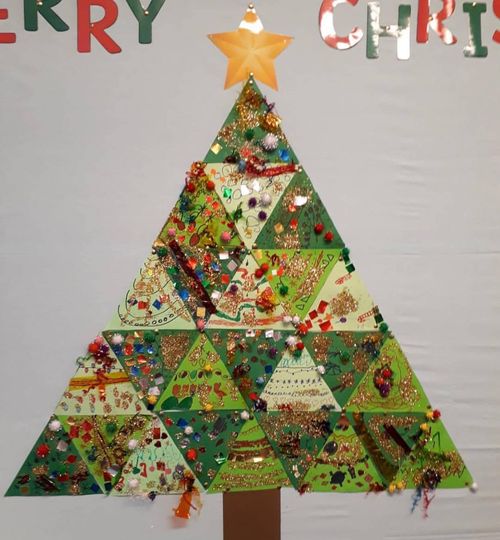 A Christmas tree is made from several decorated green triangles in different shades. They come together to form one large triangle with a star on the top and a stem on the bottom.
