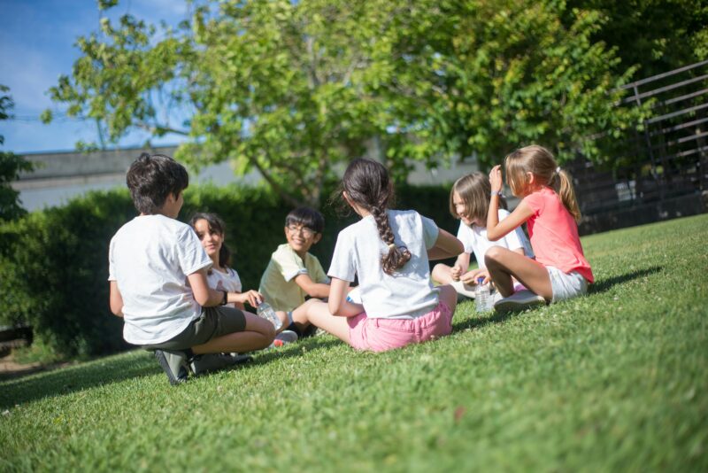 Kids playing a circle game on grass as an example of outside time for kids