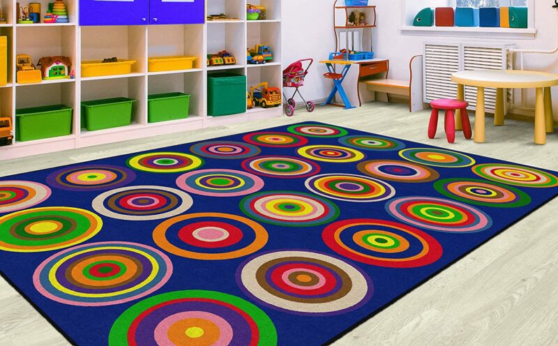A bright blue rug has 24 multi-colored circles in a 6 x 4 pattern. 