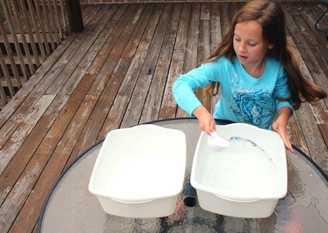 Young student scooping water from one plastic container to another (Circulatory System Activities)