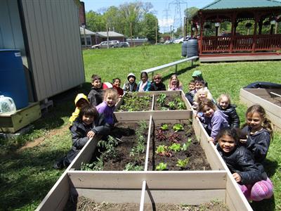 students sitting by an outside garden for a green school idea 