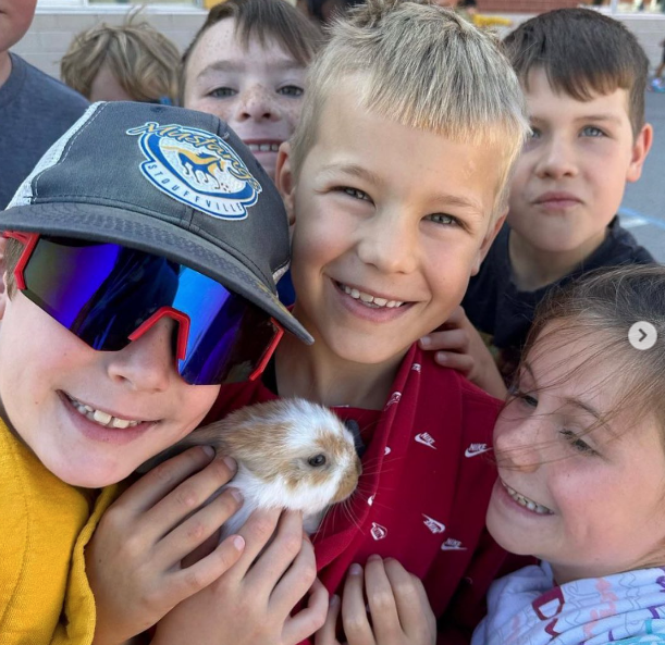 Excited children gather around a lop eared bunny as an example of best classroom pets