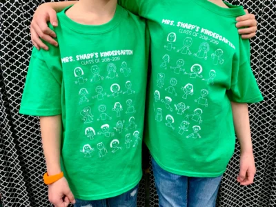 Two kindergarten students wearing green shirts to celebrate their graduation.