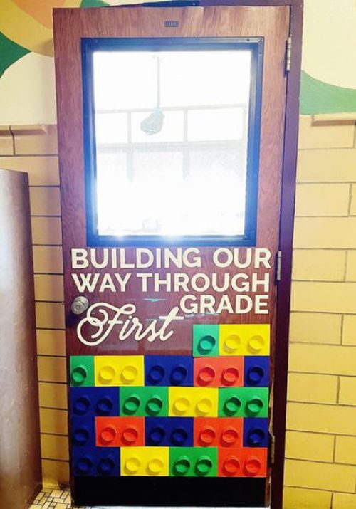Lego themed classroom door. Text reads We're building our way through 1st grade.