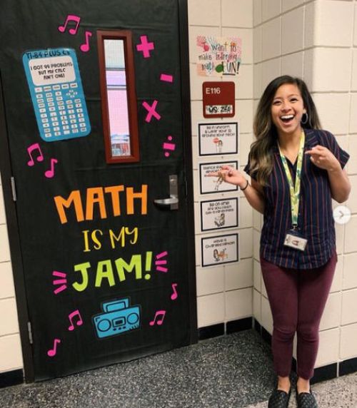 Teacher standing my classroom door that reads Math is my Jam with pictures of math symbols and a calculator